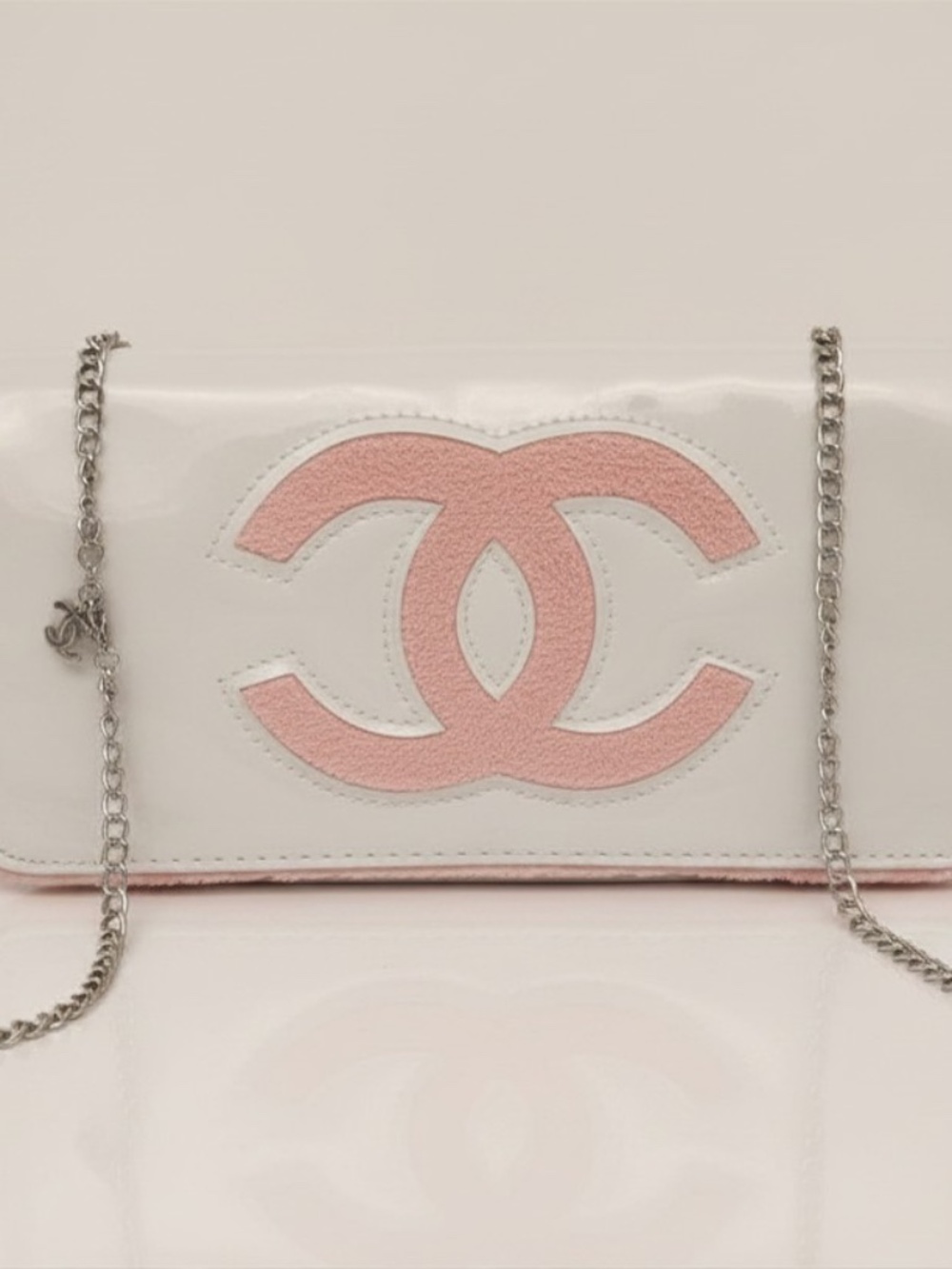 Chanel Beauty Bag features a white patent leather exterior with a prominent pink